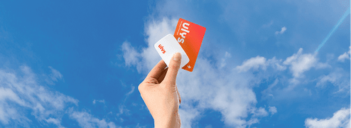 Main tenant deux cartes de service levées vers un ciel bleu avec quelques nuages.