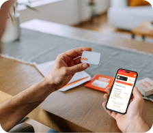 Personne tenant une carte et un smartphone affichant une application, posés au‑dessus d’une table avec d’autres cartes.